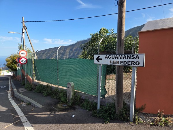 Panneau indiquant Aguamansa et un bebedero, avec vue latérale sur la crête forestière.