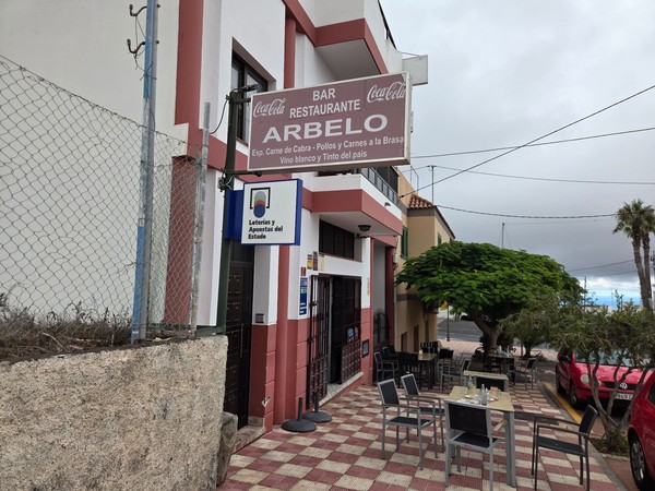Façade du Bar Restaurante Arbelo avec terrasse sur trottoir, enseigne Coca-Cola et tables extérieures prêtes à accueillir les clients.