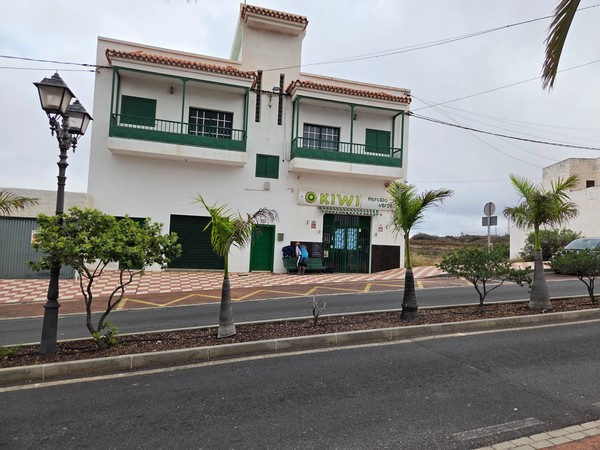 Devanture de O KIWI Mercado Verde, petite épicerie de quartier avec balcon vert et volets assortis.