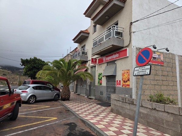 Entrée du supermarché Superdíplo avec palmier et stationnement juste devant le magasin.