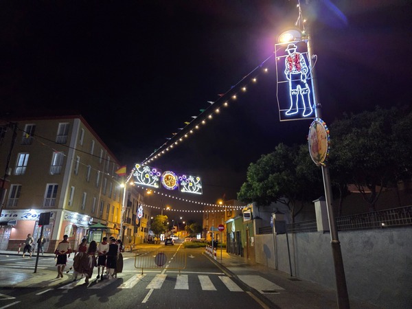 Entrée de rue illuminée avec guirlandes et silhouettes folkloriques pendant le Baile de Magos de La Laguna.