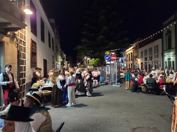 Ruelle de La Laguna bondée de participants en chapeau et jupe rayée, ambiance conviviale.