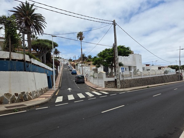 Rue en pente de Bajamar bordée de maisons et de palmiers.