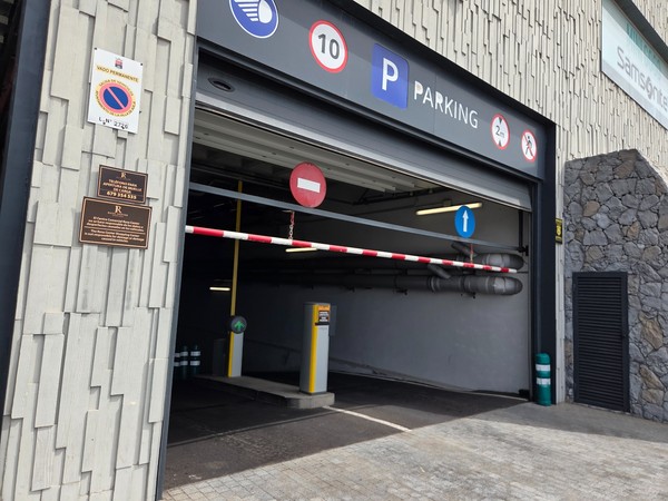 Rampe d’accès au parking du Rosa Center avec signalisation claire et barrière d’entrée.