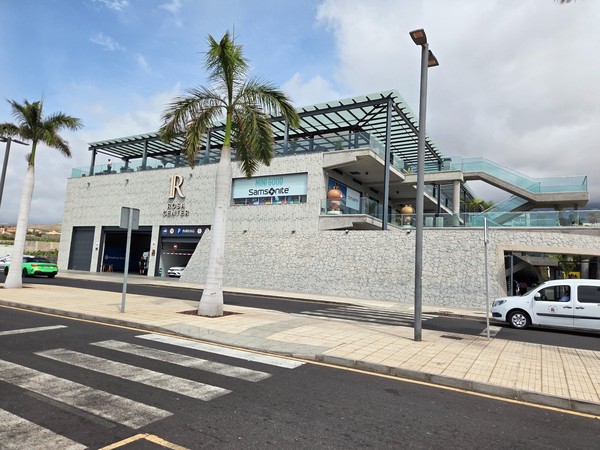Vue extérieure du Rosa Center à Playa Paraíso, avec palmiers, façades vitrées et escalier donnant accès aux différents niveaux.