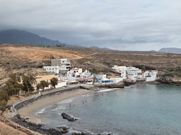 Vue panoramique d’El Puertito de Adeje, la plage de sable et les maisons blanches au fond de la baie.