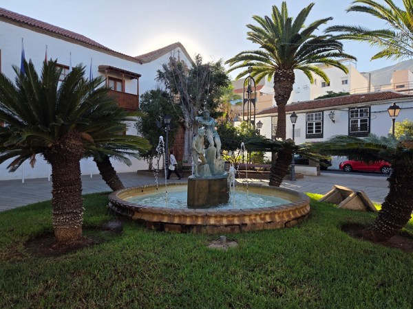 Fontaine circulaire ornée de statues au milieu d’une pelouse et de palmiers à Güímar.