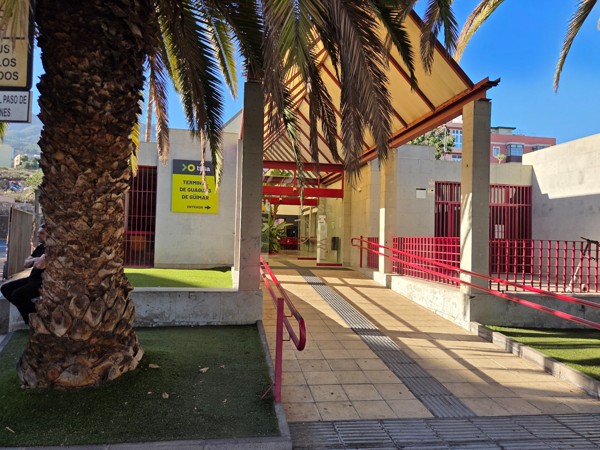 Entrée de la station de guaguas de Güímar avec rampes rouges et palmiers.