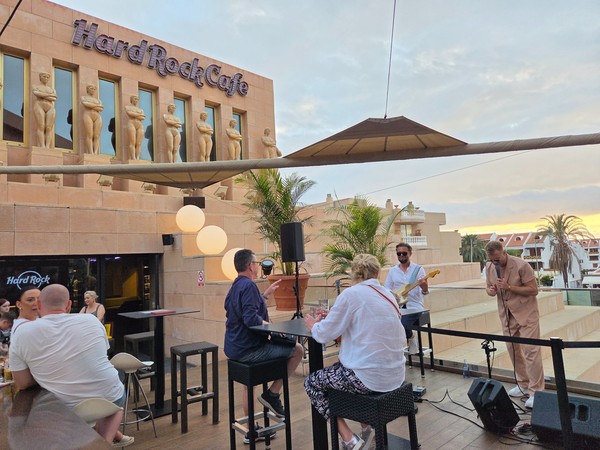 Concert acoustique en terrasse au Hard Rock Cafe Tenerife avec vue sur les palmiers.
