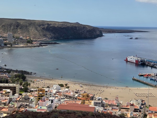 Vue panoramique sur la baie de Los Cristianos avec la plage de sable doré et le port de ferries à Tenerife.