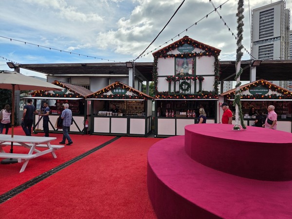 Cabanes centrales du marché de Noël devant El Corte Inglés, décorées de guirlandes, de boules rouges et dorées, accueillant les visiteurs.