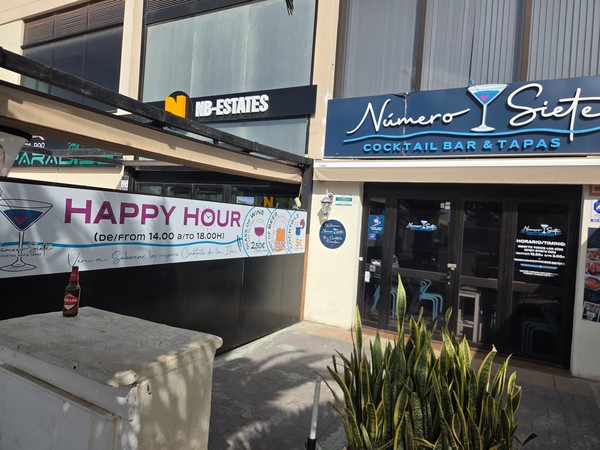 Entrée du cocktail bar et tapas Número Siete à Palm-Mar avec enseigne bleue et grande bannière Happy Hour devant la terrasse.