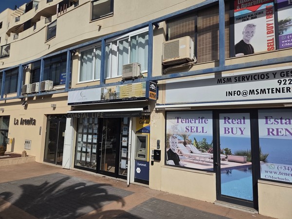 Façades d’agences immobilières à Palm-Mar avec vitrines d’annonces et panneaux Tenerife Sell Buy Rent.