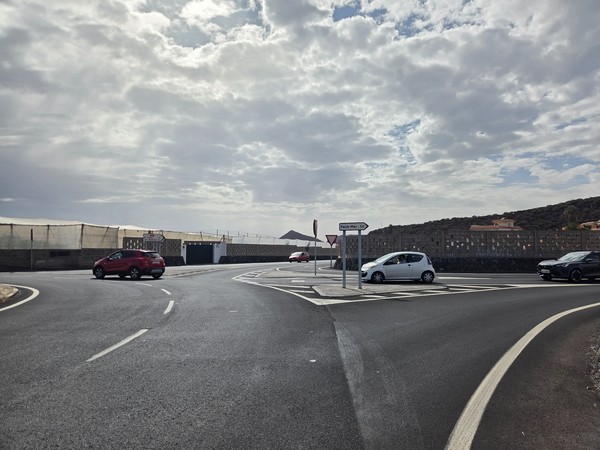 Carrefour routier avec panneau indiquant Palm-Mar, des voitures circulant sous un ciel partiellement nuageux au sud de Tenerife.