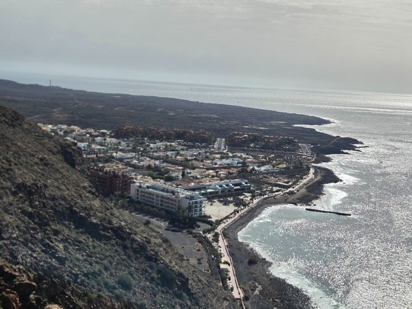 Vue aérienne de Palm-Mar depuis la montagne voisine, montrant les immeubles en bord de mer, la promenade côtière et la côte rocheuse du sud de Tenerife.