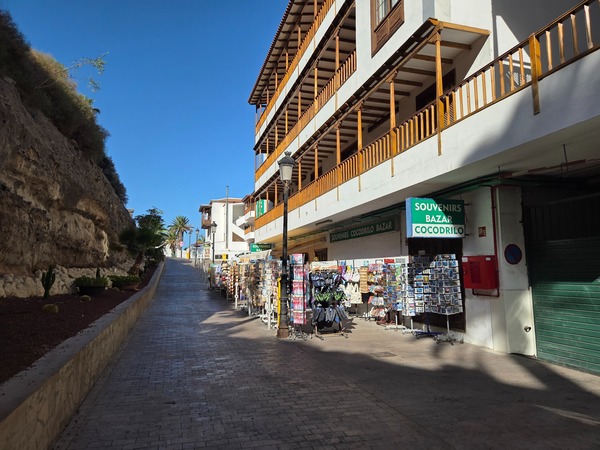 Allée en pente avec boutiques de souvenirs menant vers la Playa de Los Guíos.