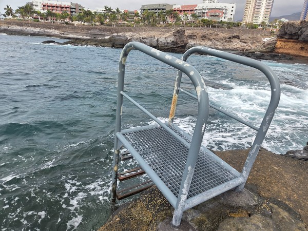Gros plan d’une échelle métallique fixée à la roche à El Marquéz, idéale pour se baigner dans une eau claire.