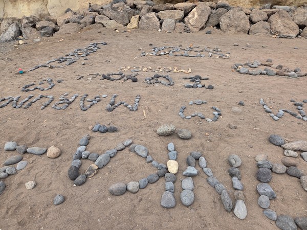 Mots et dessins composés de galets sur le sable de Playa Las Galgas.