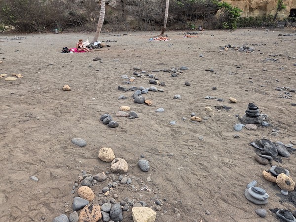 Étendue de sable avec petits cairns et pierres volcaniques à Playa Las Galgas.