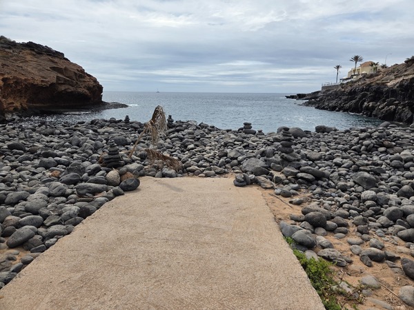 Extrémité de la rampe en béton donnant sur les galets noirs et l’anse de Playa Las Salinas.