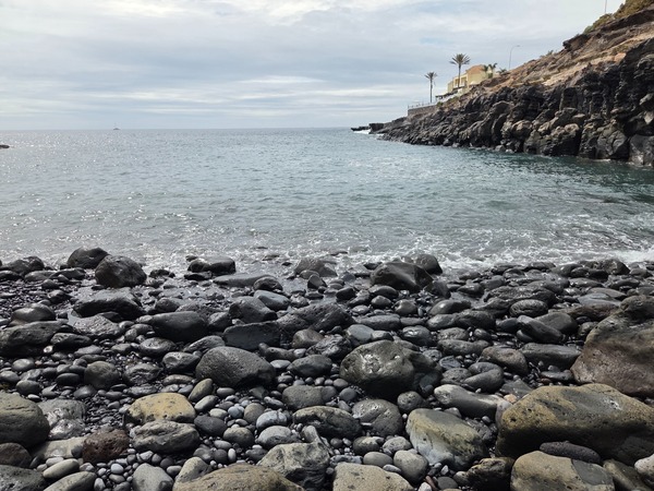 Galets de basalte noir mouillés par les vagues sur le rivage de Playa Las Salinas.
