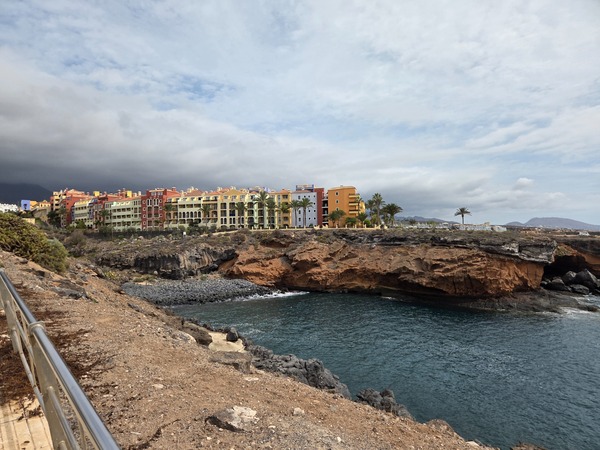 Panorama de Playa Las Salinas à Adeje, une crique entourée de falaises volcaniques avec des bâtiments colorés en arrière-plan.