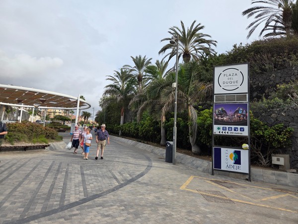 Totem d’entrée indiquant Plaza del Duque sur la promenade bordée de palmiers, à 250 mètres du centre commercial.