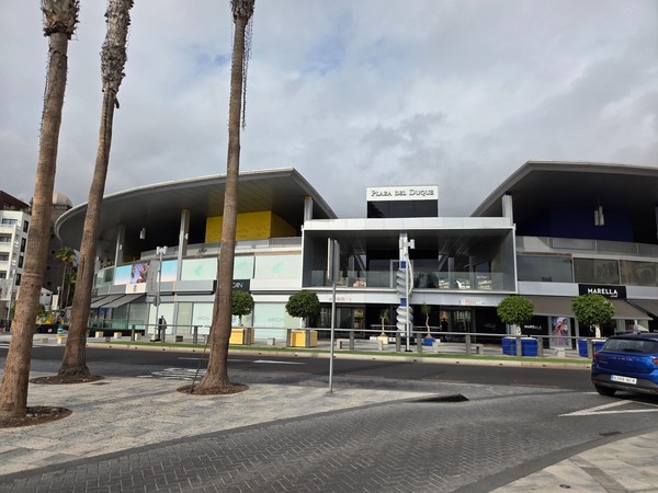 Façade moderne du centre commercial Plaza del Duque à Costa Adeje, avec grandes baies vitrées et auvent courbe.