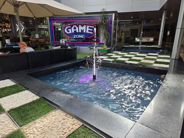 Bassin avec fontaines et éclairage animé près de la Game Zone, espace ludique au cœur des galeries.